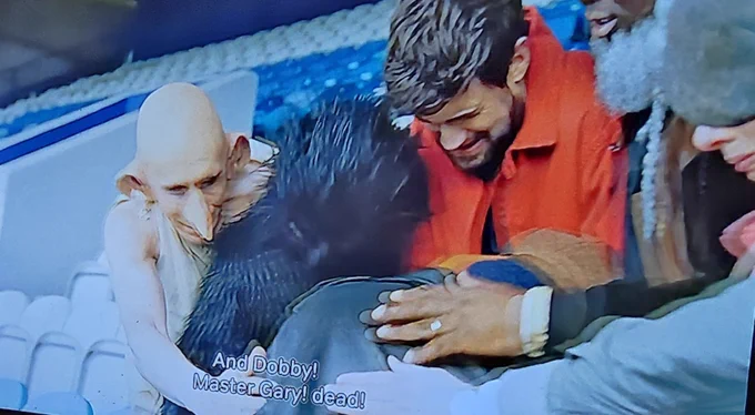 The second scene captures a chaotic and emotional huddle within the same stadium stands, blending realistic and fantastical elements. A character resembling the house-elf Dobby appears on the left with a sorrowful expression, while several other people lean in toward a central figure, their faces etched with grief. A hand with a visible ring rests on the back of someone in the center, emphasizing a sense of shared loss. The subtitles, "And Dobby! Master Gary! dead!", punctuate the somber atmosphere, signaling a tragic turn in this unusual crossover story.