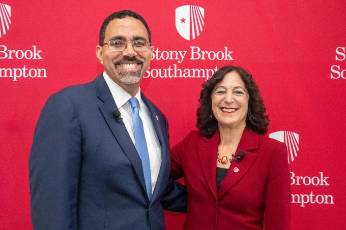 Stony Brook Univeristy President Andrea Goldsmith and SUNY Chancelor John B. King Jr. stand next to each other in front of a red back drop with the words "Stony Brook Southampton."