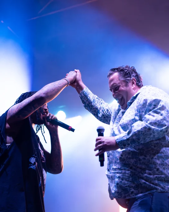 Waka Flocka Flame dapping up Coach Eck on stage under bright lighting.