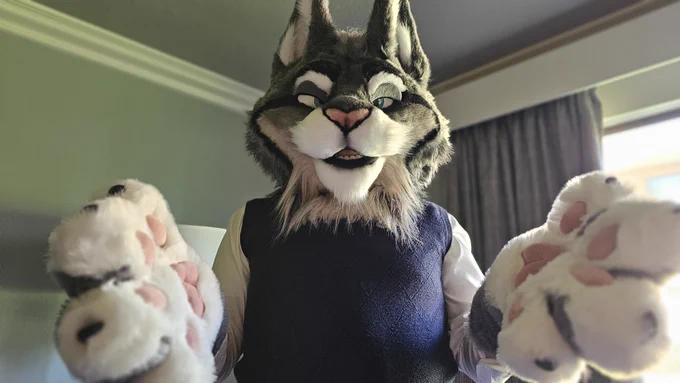Milton Lynxley from Zootopia 2, an older gray Canadian lynx character wearing a blue sweater vest and white shirt, holding his paws out toward you in an inviting manner.