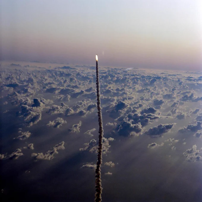 Aerial views of the STS-5 launch as seen from T-38 chase aircraft Nov. 11, 1982. Shuttle Columbia can be seen as a small figure blazing into the sky, trailed by a line of exhaust.