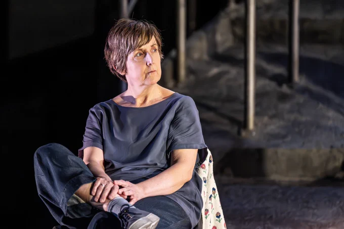 A photo showing a woman looking brooding on a darkened stage 