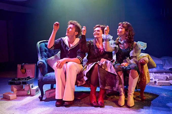 A photo showing three performers pointing upwards 