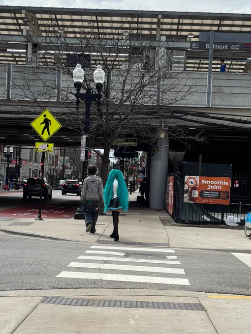 a hatsune miku cosplayer walking by the belmont red/purple/brown line station in lake view, chicago
