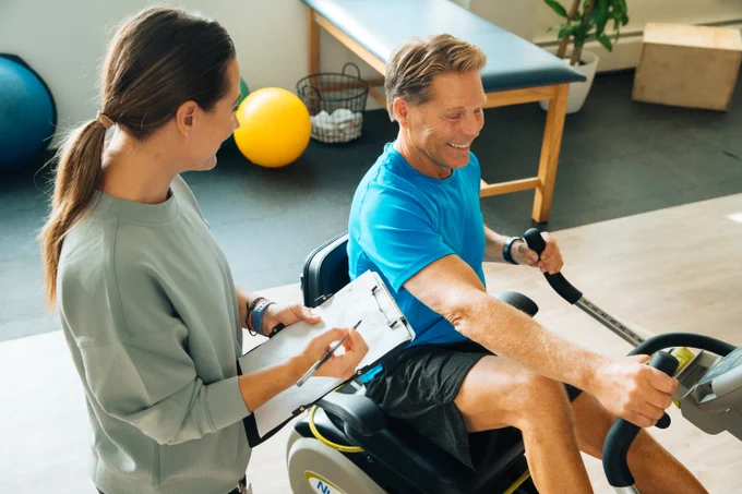 Senior man exercising on the NuStep T4r recumbent cross trainer seated stepper at a physical therapy session 