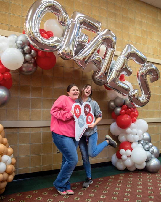 Students posing with an Ohio State sign in front of a balloon arch at the student carnival