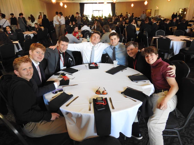 Steel Bridge Team dressed up with their arms around each other at a banquet table.