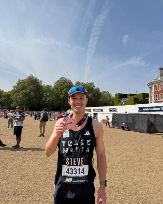UKPN runner smiles at the camera and holds his London Marathon medal.