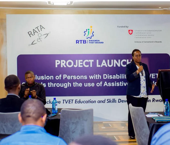 A woman speaks at a podium while sing language interpreter assists