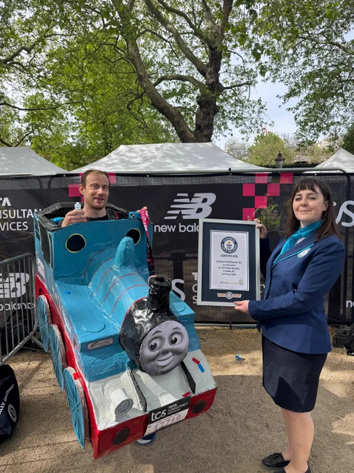 a man dressed in a blue thomas the tank engine costume poses next to a female Guinness World Records adjudicator 