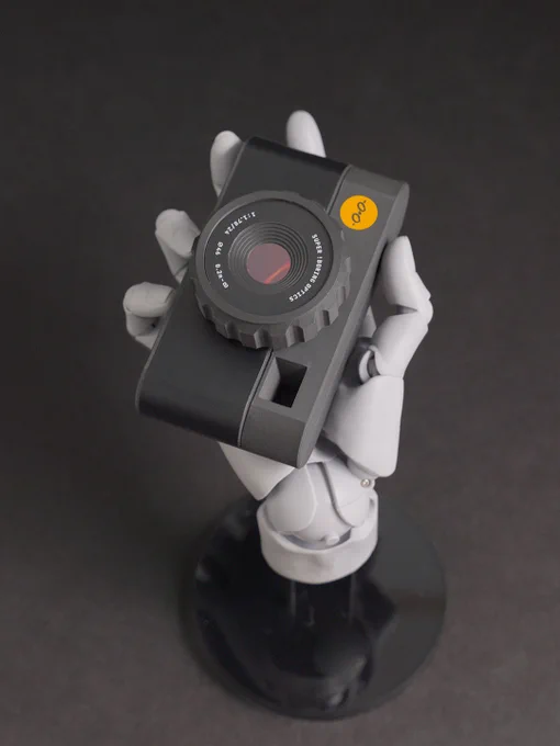 A robotic hand holds a vintage-style camera against a dark background, emphasizing the camera's design and functionality.