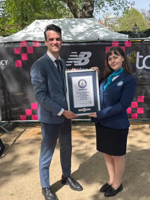 a man in a suit and dress shoes receives the guinness world records certificiate