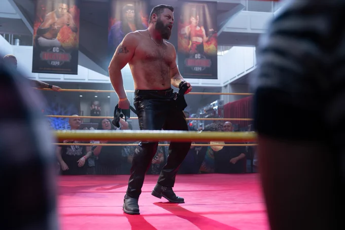 From Margo’s Got Money Troubles. Nick Offerman as Jinx is in the wrestling ring with his shirt between his legs.
