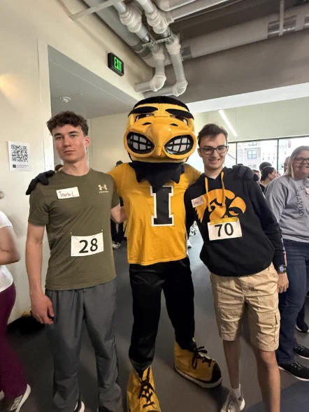 Two UI REACH students stand with Herky the Hawk.