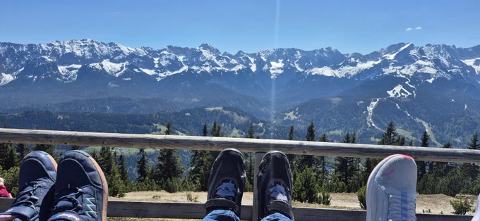 Im Vordergrund Füße liegen auf einer Sonnenliege mit Ausblick auf die Zugspitze 