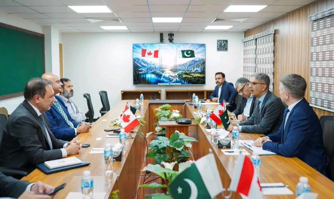 Conference room setting, with Canadian and Pakistani flags prominently displayed in the room. 