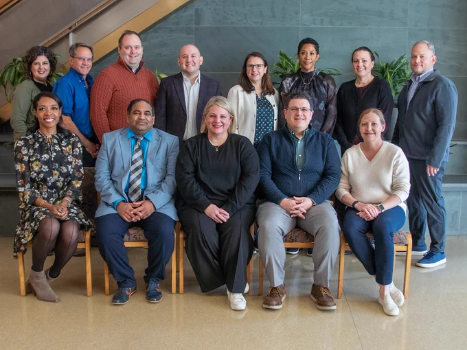 Group photo with eight people standing and five people sitting.