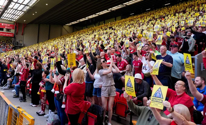 Thousands of LFC fans hold up yellow protest cards on The Kop. Image is copyright Alamy.