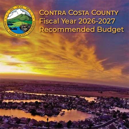 The cover of the Contra Costa County Fiscal Year 2026-2027 Recommended Budget. The image features a scenic aerial view of a residential waterfront community at sunset, with golden and purple clouds filling the sky. In the top left corner is the official Seal of Contra Costa County, California. To the right of the seal, gold text reads: "Contra Costa County Fiscal Year 2026-2027 Recommended Budget.