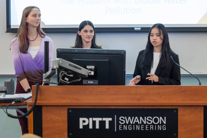 Three Swanson School first-year students present their paper at a lectern