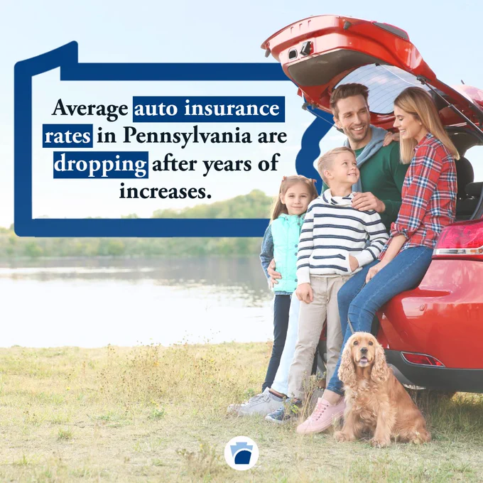 A family sits in the trunk of their car near a lake with their dog. Average auto insurance rates in Pennsylvania are dropping after years of increases.