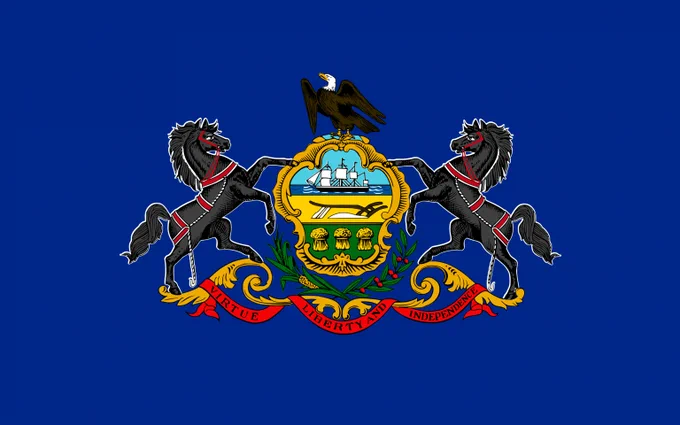 The image shows the Pennsylvania state flag, featuring a blue field with a central coat of arms, flanked by black horses, an eagle atop, and a red ribbon reading "Virtue, Liberty, and Independence."