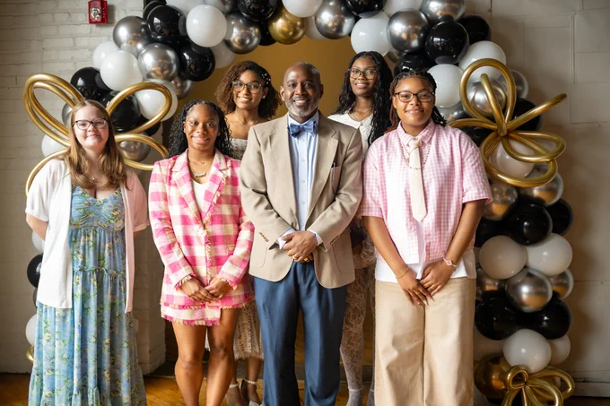 Six individuals pose for a picture and smile.