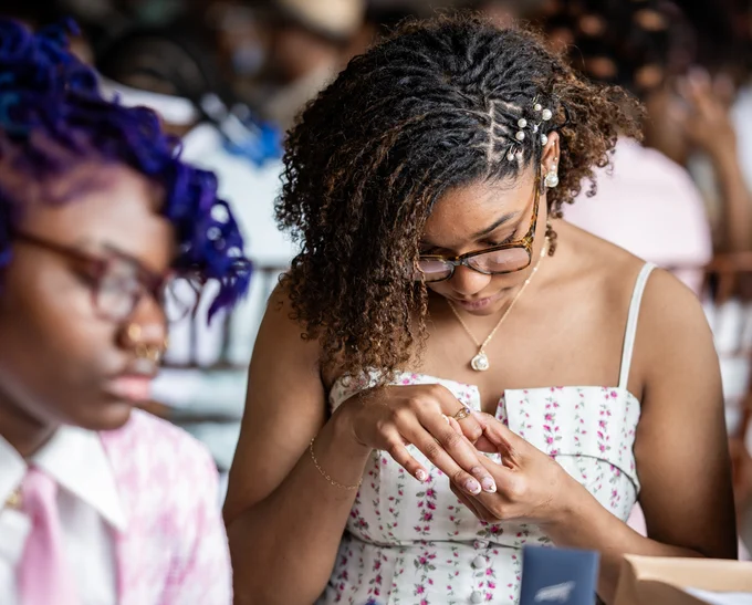 A student puts a ring on her finger.