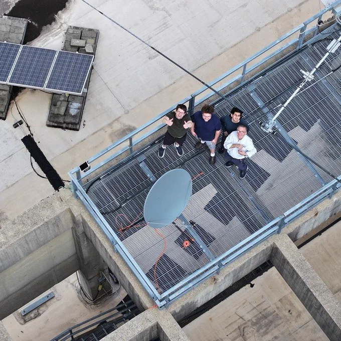Jake Wendt, Sebastian Shaffer, Taimur Ilahi, and Juan Manfredi on the roof of Benedum Hall standing near a satellite dish and a radio antenna.