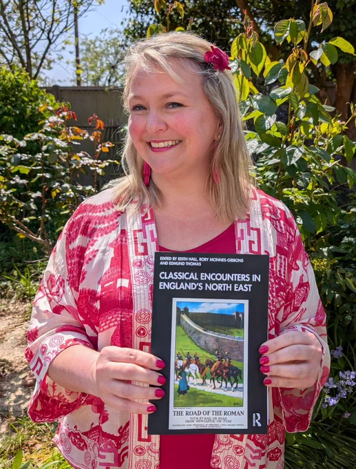 Woman holding book with foliage in background