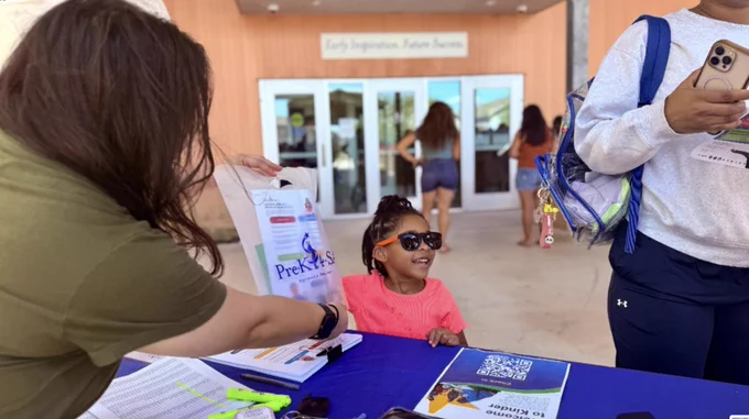 A woman having a child a Pre-K 4 SA branded bag at Welcome to Kinder.