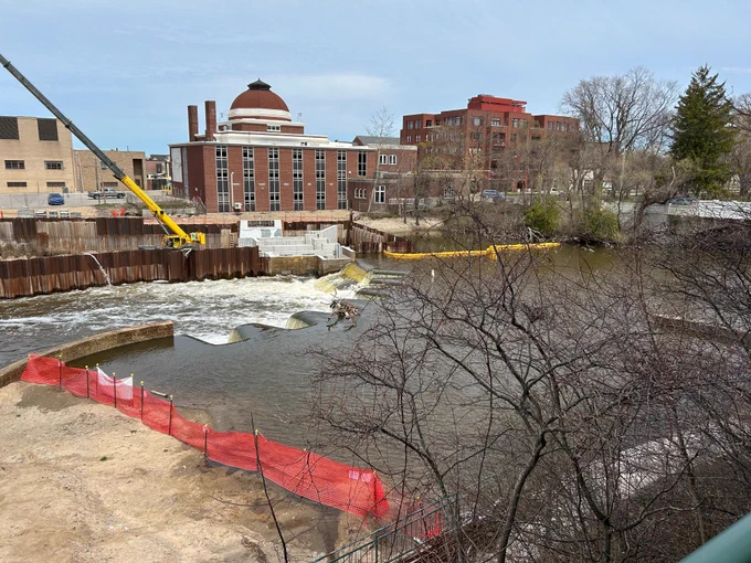 Water flows through Union Street Dam. A construction vehicle is on site conducting work.
