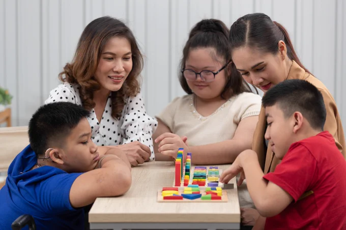 Three Special Education needs students learning about shapes with the helps of their teachers