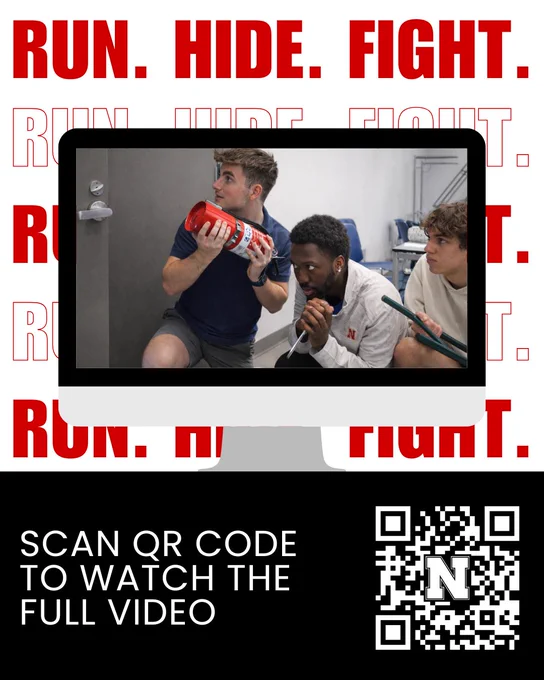 Promotional graphic for a campus safety video with large red text repeating “RUN. HIDE. FIGHT.” in the background. In the center, a computer screen shows three students crouched in a classroom, appearing alert and hiding near a door; one holds a fire extinguisher. At the bottom, text reads “Scan QR Code to Watch the Full Video” next to a QR code featuring an “N” logo.