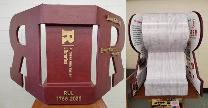A sculpture resembling a red book with the Rutgers University Libraries logo and text "RUL 1766-2026" on the cover. The open pages display graphics and information about Rutgers University Libraries, including library statistics and services.