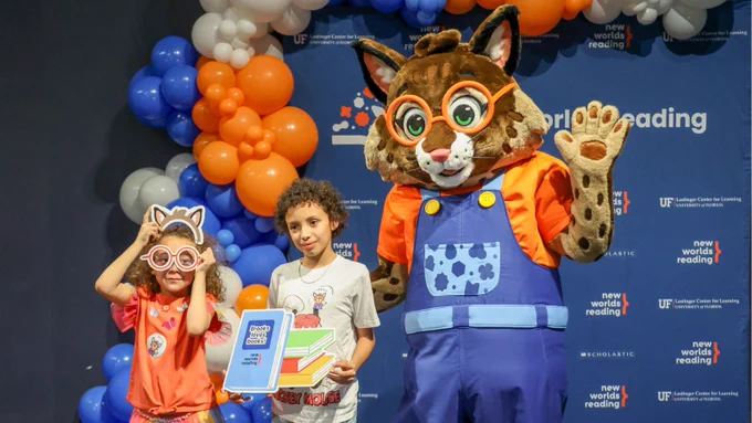 Two kids standing next to Brooks the Bobcat.