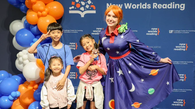 Three children standing and smiling next to Ms. Frizzle.