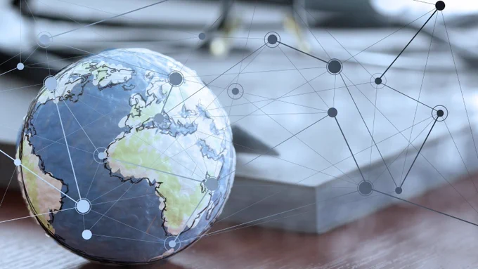 A globe on a desk with connecting dots and lines graphics on top