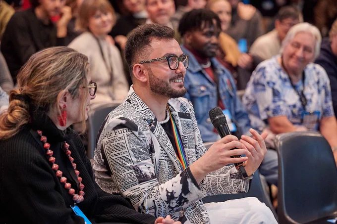 Hüseyin Ali Kudret speaking in a crowd at a conference.