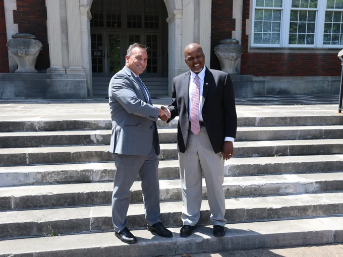 Dr. Mike Daria shakes hands with Cognia official Andre Harrison, Cognia’s deputy chief of accreditation services.