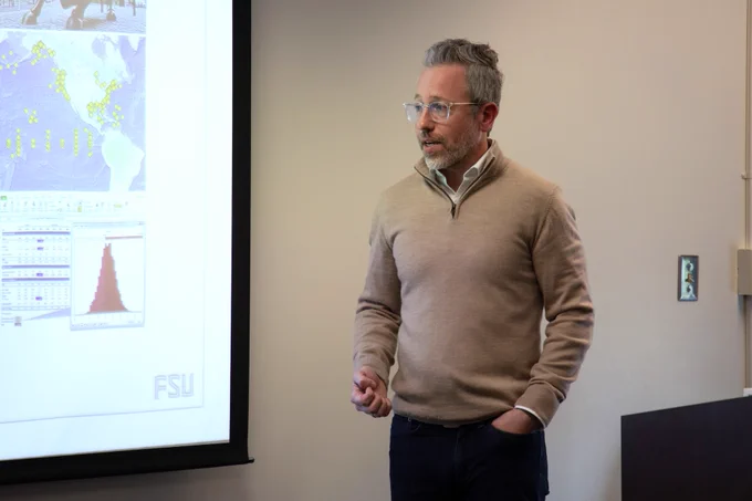 Michael Alvarado presents in front of a projected powerpoint.