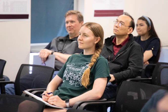 The image focus is on four audience members smiling as they listen to a presentation at the annual CS Expo. 