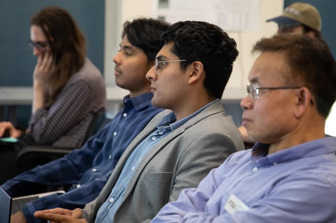 The image focus is on three audience members intently listening to a presentation at the annual CS Expo. 