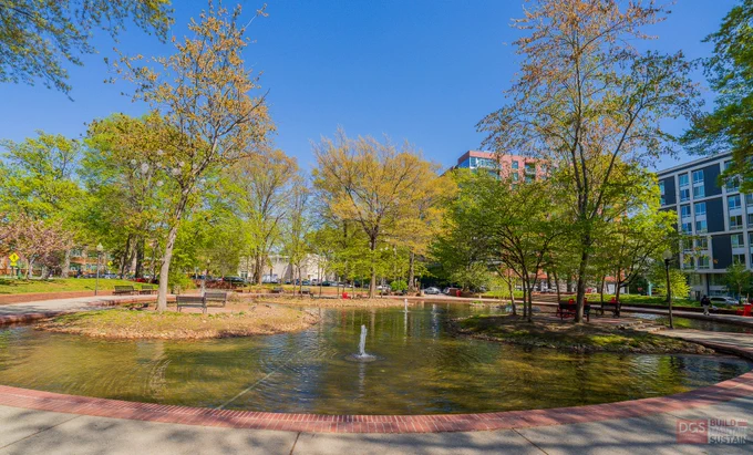 Clear water fountains flow in a serene urban park SW Duck Pond surrounded by green trees under a bright blue sky