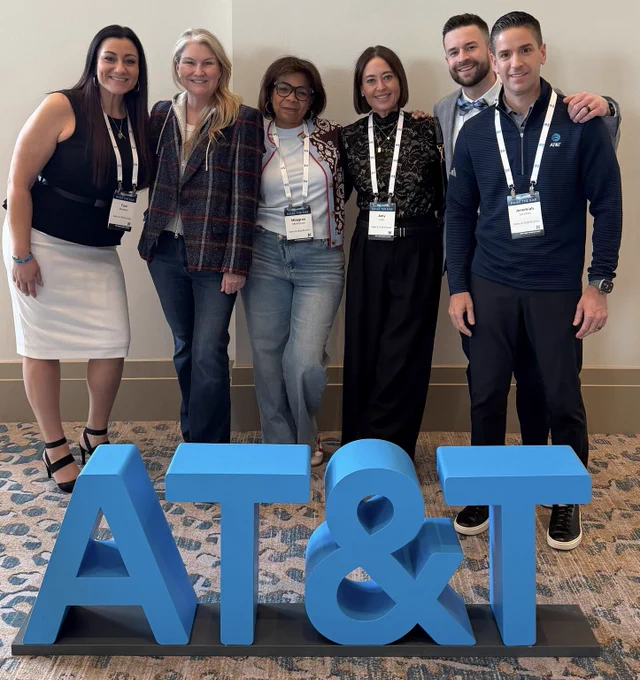 Team members pose for a photo behind AT&T logo blocks