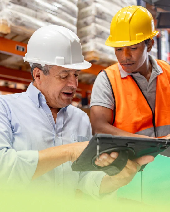 Two manufacturing professionals look over a tablet while on the job site.
