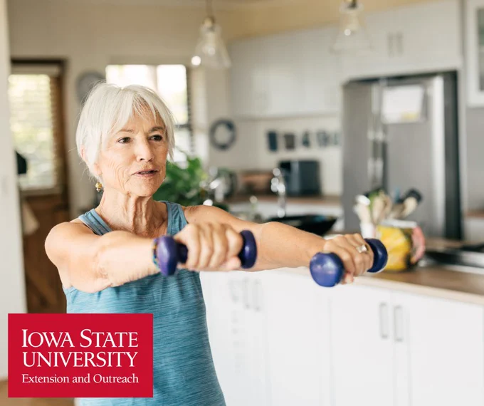 Senior woman exercising with small dumbbells in a  kitchen setting at home