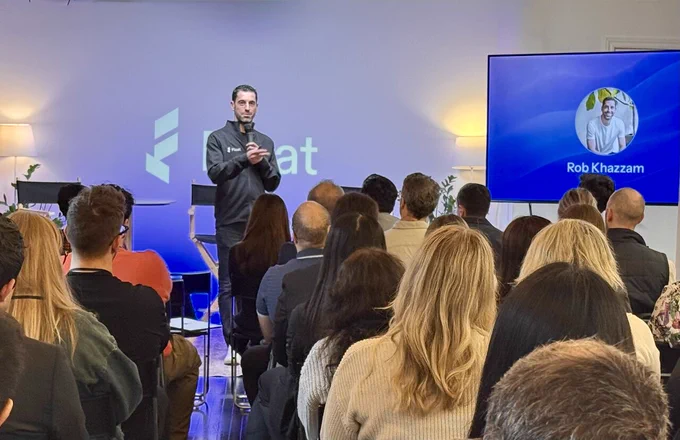 Float CEO Rob Khazzam is speaking to an audience at a Float Forward conference with presentations on a screen. The background shows the Float logo and there is a screen displaying an image and the name "Rob Khazzam."