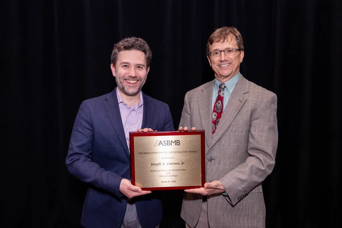 Joseph Cotruvo, Jr. (left), winner of the 2026 ASBMB Mildred Cohn Young Investigator Award, and J. Martin Bollinger Jr. (right) pose for photo holding the award at the 2026 ASBMB Annual Meeting.