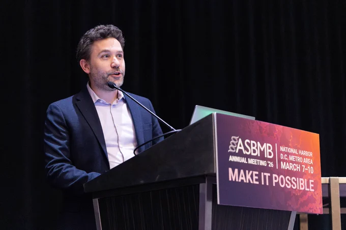 Joseph Cotruvo, Jr., winner of the 2026 ASBMB Mildred Cohn Young Investigator Award, stands at a podium delivering his talk at the 2026 ASBMB Annual Meeting.